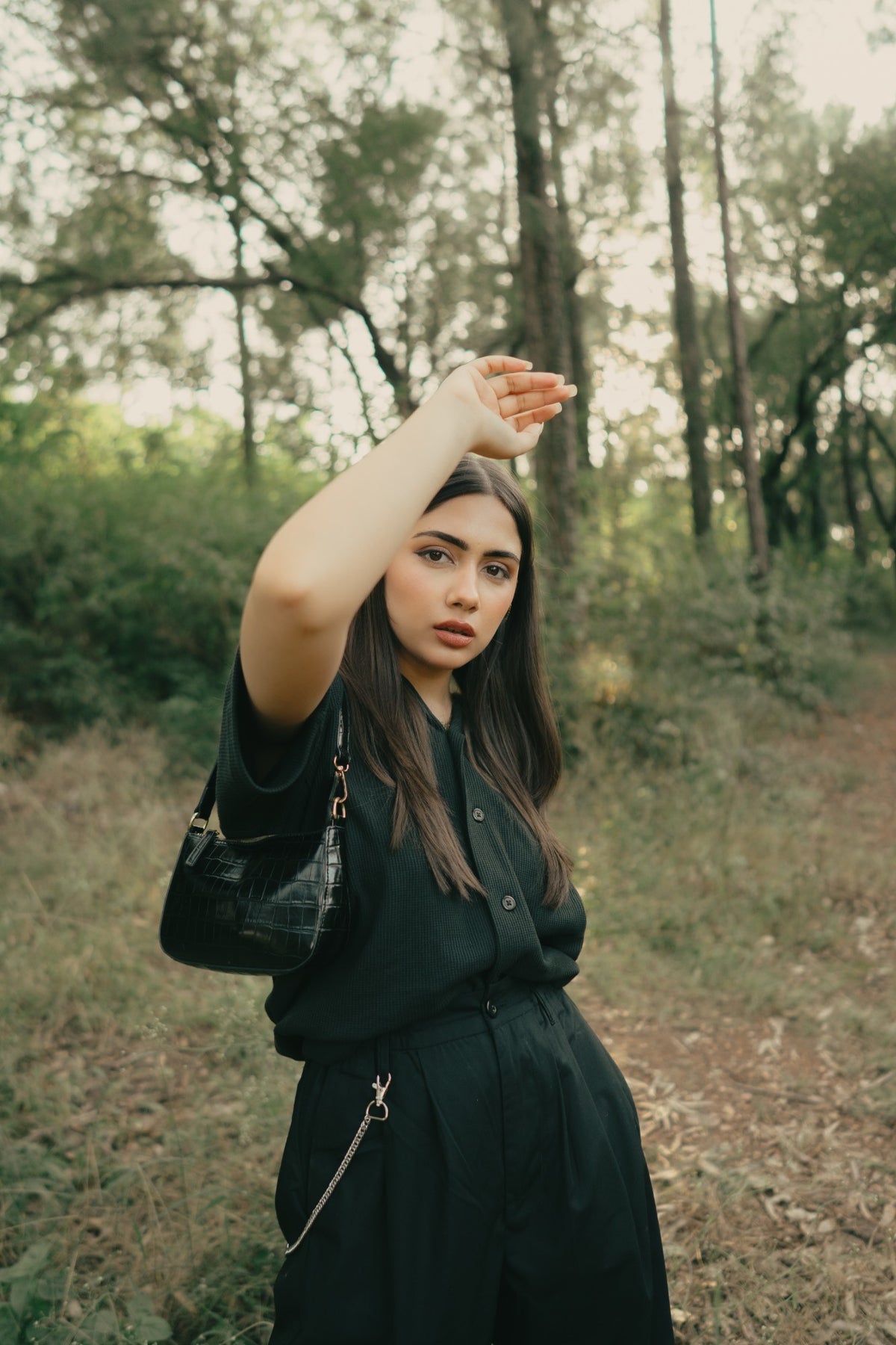 Model in the black Cuban collar shirt raising an arm against the light
