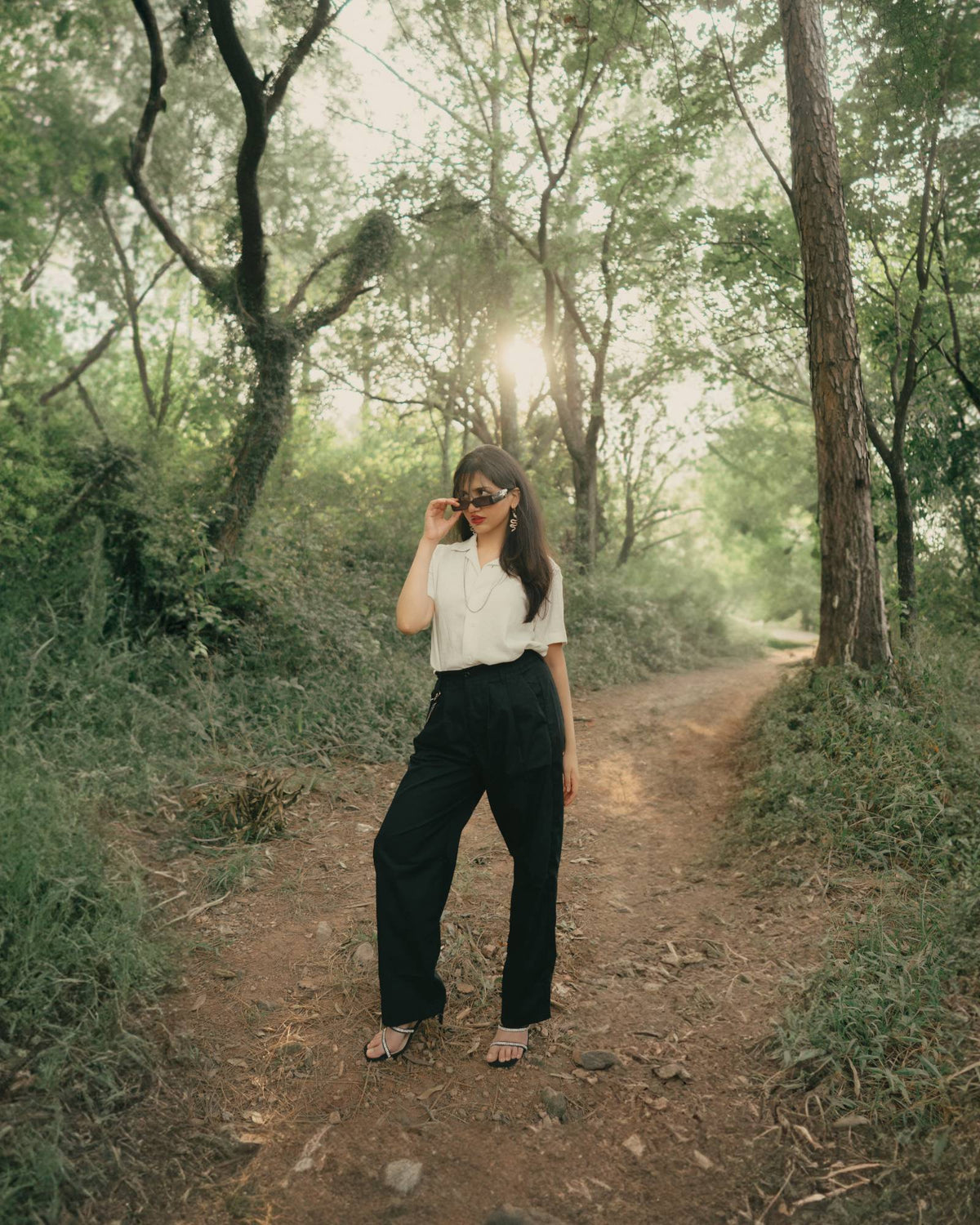 Model in the off-white Cuban collar and black trousers on a sunlit forest path